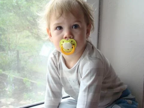 The child sits on the window Stock Photos