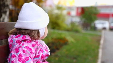 Child sitting alone on a bench. Stock Footage 68399317