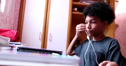 Child sitting down at desk opens laptop and turns computer on preparing to do Video stock 144297655