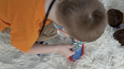 Child sitting on the floor on a light blanket, squeezes tablets from the package Stock Footage 128072472