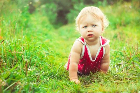 The child is sitting on the grass 库存照片