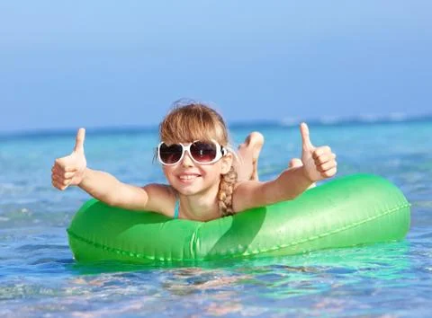 Child sitting on inflatable ring thumb up. Stock-Fotos