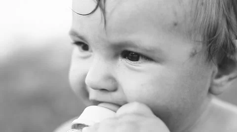Child sitting on the lawn and drinking milk from a bottle. Stock Footage 50260331