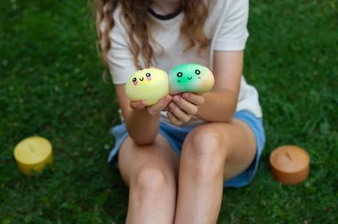 Child sitting outdoors while holding two dumpling squishy toys. Stock Photos