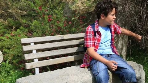 Child sitting on a park bench  Stock Footage 75334442