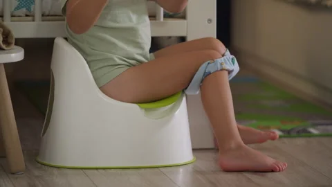 Child sitting on potty with tablet in bedroom in evening Stock Footage 295278548