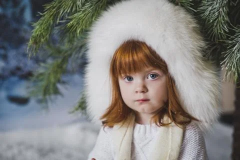 The child is sitting in the snow under the tree 4538. Stock Photos