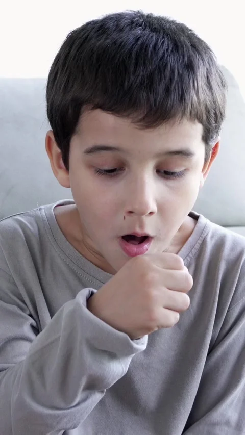 Child sitting on sofa at home and holding hand on chest. Vídeos de archivo 337033817