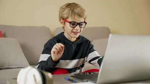 Child sitting on the sofa thinking, using laptop for e-learning Stock Footage 231707654