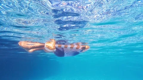 Child sitting in striped inflatable float playing water games in swimming pool Stock Footage 344831895