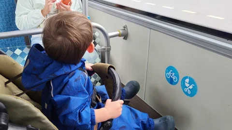 Child sitting in stroller on public transport. Little boy looking through window Stock Footage 340405960