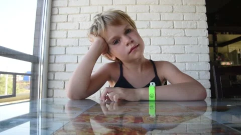 The child is sitting at a table in a cafe and is bored. Stock Footage 142919947
