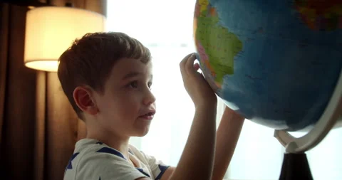 Child sitting at a table at home in soft sunlight, carefully looking at the Stock Footage 317919099