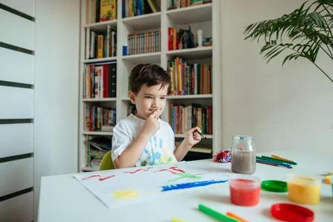 Child Sitting at Table Thinking About his Painting. Stock Photos