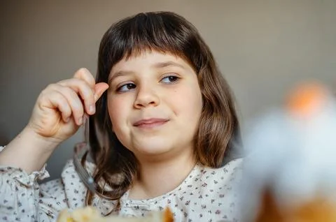 Child sitting thoughtfully at the table in a cozy home environment. 스톡 사진