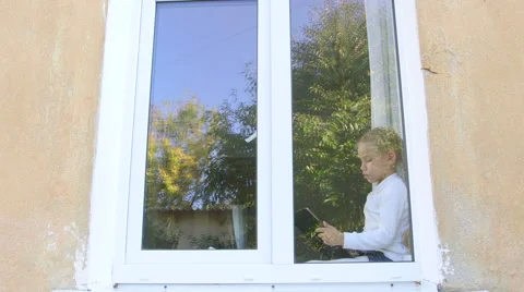 Child sitting by the window and playing with digital tablet Stock-Footage 43348437