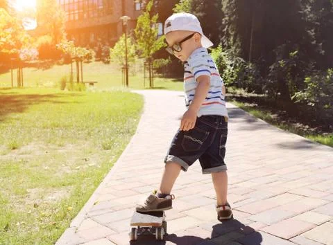 Child with skateboard on the street at sunny day. Stock Photos