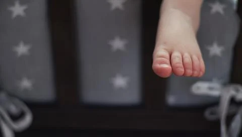 The child is sleeping in bed, his leg is hanging down. leg of a little sleepi Stock Photos