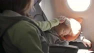 Child Sleeping On Seat Traveling By Plane. Mother Gently Stroking His Head. Stock Footage