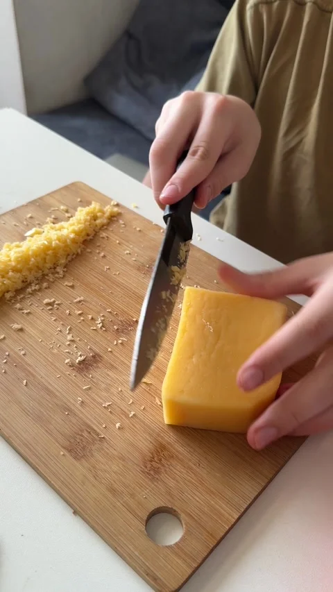 Child slicing block of cheese with knife, close-up hands, part of cheese and Stock Footage 337338958