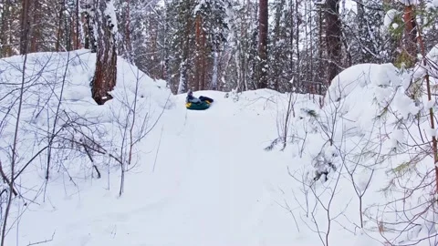 Child slides down in a snowy forest Stock Footage 148422596