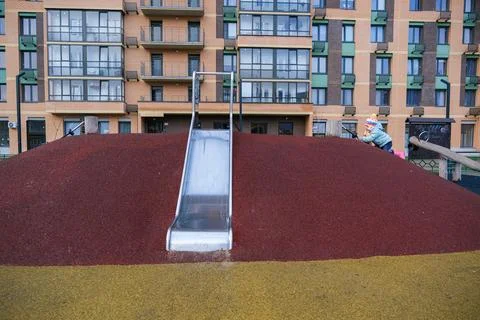 A child is sliding down a slide in front of a building Stock Photos