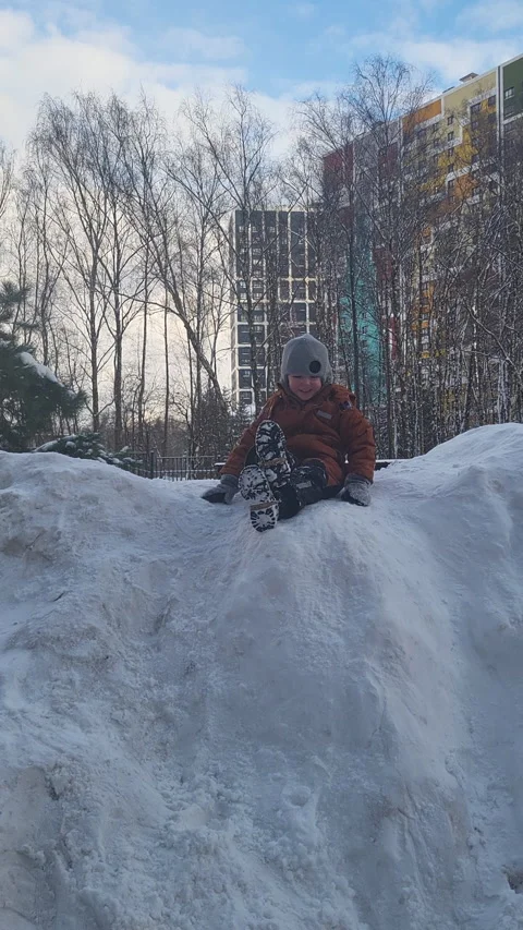 Child sliding down snowy hill in park. Happy boy playing outside during winter Stock Footage 336393564