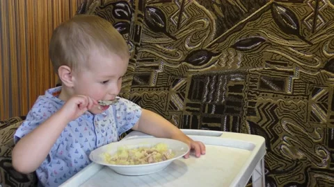 A child at a small table eats food Stock Footage 132507842