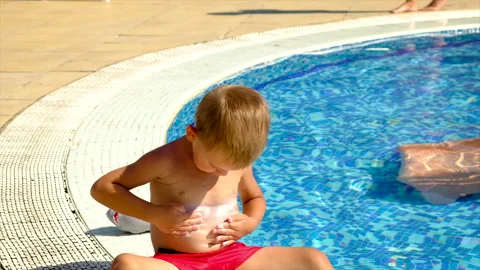 A child smears sunscreen by the pool. Selective focus. Stock Footage 165333947