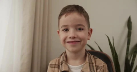 Child smiling child looking at camera are sitting on the couch at home, cute Stock Footage 240945642