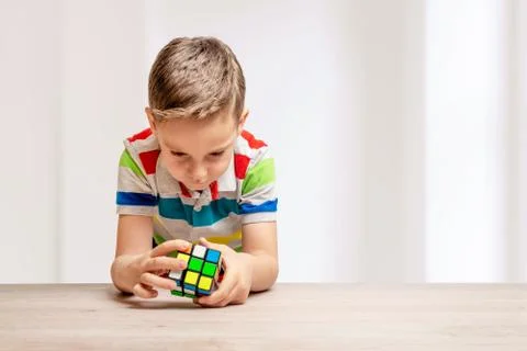 Child solves a rubik's cube. Concept of speedcubing puzzle competition. Copy  Stock Photos