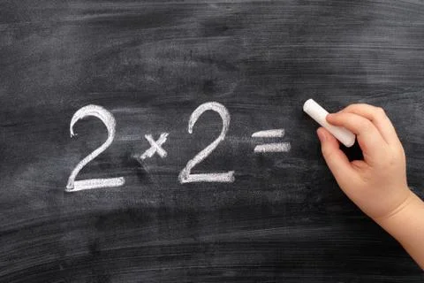 Child solving math problem on the blackboard Stock Photos
