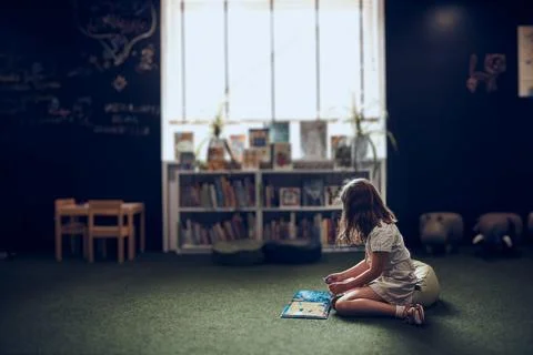 Child solving riddle in book in school library. Primary school pupil is inv.. Stock Photos