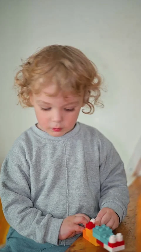 A child spends time assembling colorful building blocks on a wooden surface in 库存影片 337112495