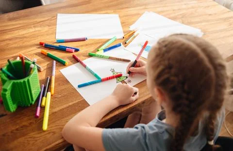 The child spends time creating and drawing. A girl draws a Christmas tree with Stock Photos