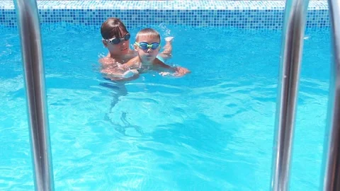 Child spends time in the pool with his brother, learns to swim in pool. Slow Stock Footage 122224467