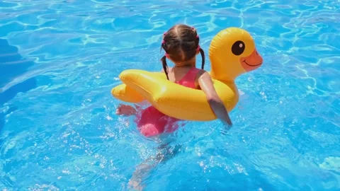 A child splashes in the pool water on the resort's outdoor area wearing a yel Stock Footage 301404944