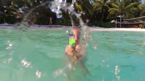 Child splashing water on camera while swimming inside the ocean during vacation. Stockbeeldmateriaal 161425877