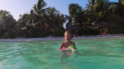 Child splashing water on camera while swimming inside the ocean during vacation. Stock Footage 161452849