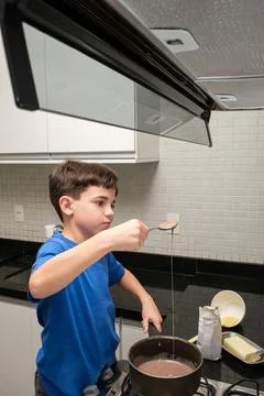 Child with a spoon checking the texture of brigadeiro, a Brazilian sweet vert Stock Photos