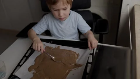 Child spreading melted chocolate on baking sheet Stock Footage 316248152