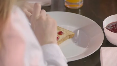 Child spreads jam or jam on a toasted piece of bread at breakfast. A close-up Stock Footage 260335261