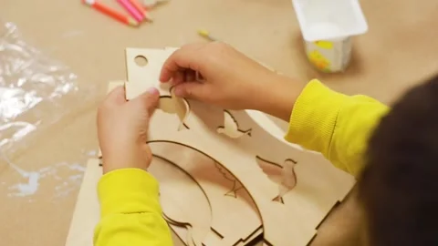 The child squeezes out a piece of a sheet of plywood crafts in the shape of bird Stock Footage 228096215