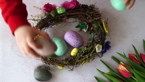 Child stacks colorful eggs in an easter wreath. Easter DIY and creativity Stock Footage 236994078