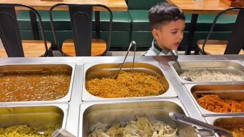 Child standing near restaurant buffet counter showcasing food choice and dining Stock Footage 339764482