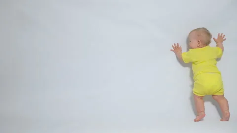 A child standing next to a white wall hits it with his palm Stock Footage 244837705