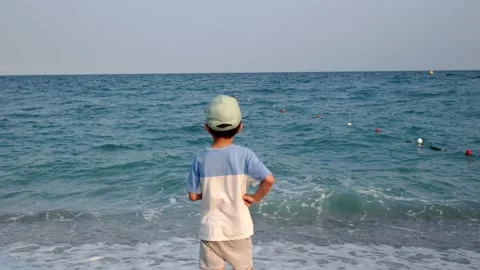 Child standing on the seashore and looking at the sea Stock Footage 201113154