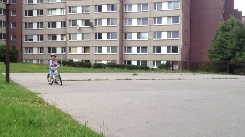 A child stands with bicycle on the playground - in the background houses 動画素材 40555643