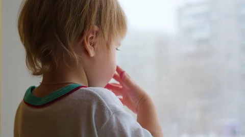 A child stands on the windowsill and looking out the window closeup Vidéo 70377107