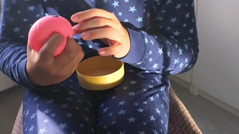 Child in star-patterned pajamas holds a pink toy while seated on a chair, with a Stock Footage 338130557